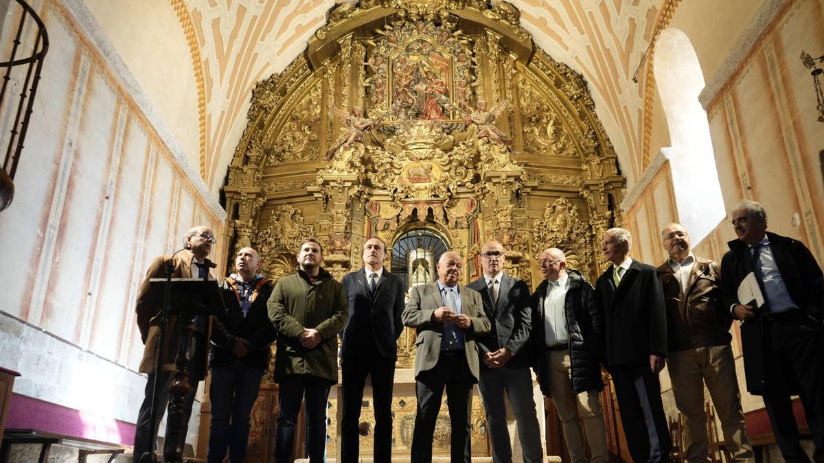 Autoridades, responsables de la Fundación Iberdrola y técnicos posan junto al retablo de la iglesia.