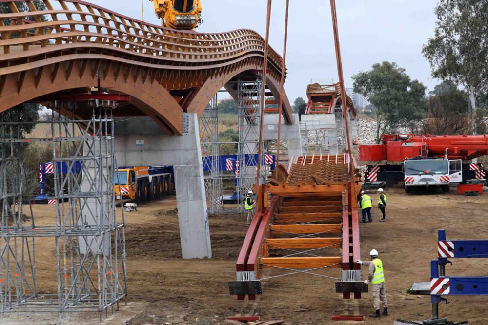 La instalación del último tramo del puente de madera sobre el río Guadalhorce ha comenzado este martes.