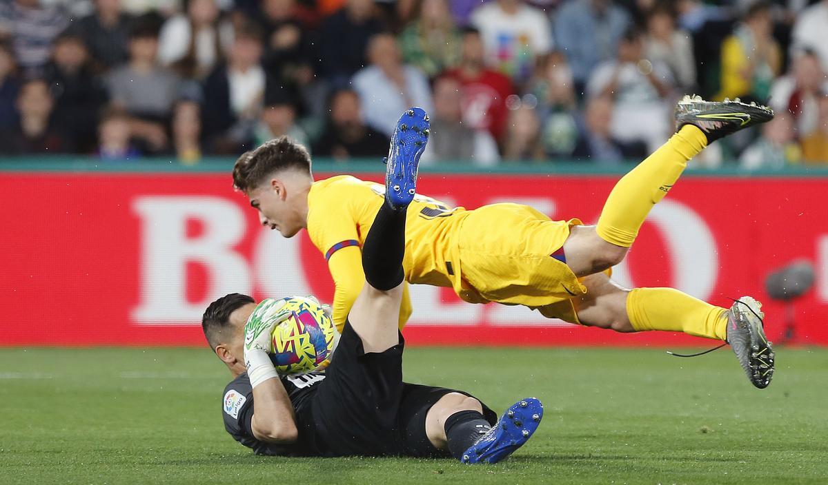 Elche (Alicante), 01/04/2023.- El centrocampista del FC Barcelona, Pablo Martín Gavi cae ante el portero del Elche Edgar Badía durante el encuentro correspondiente a la jornada 27 de primera división que disputan hoy sábado en el estadio Martinez Valero, en la localidad alicantina. EFE/Manuel Lorenzo