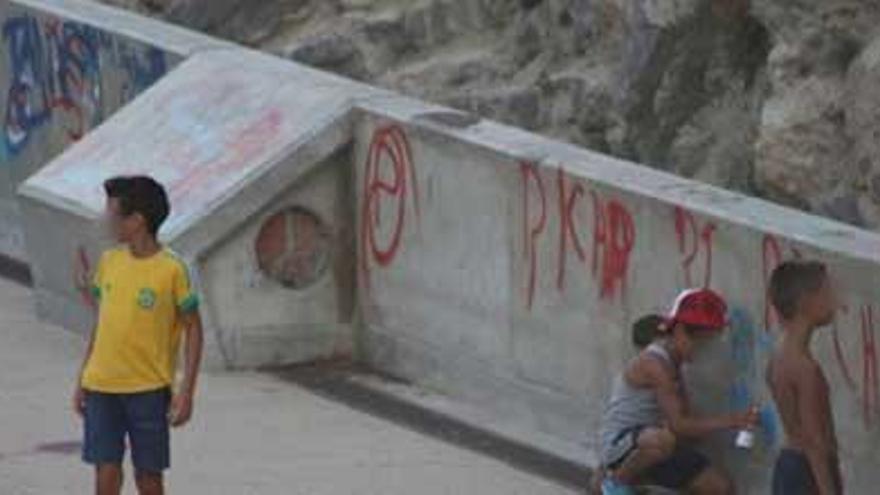 Algunos niños pintan grafitis en la plaza de sa Pedrera.