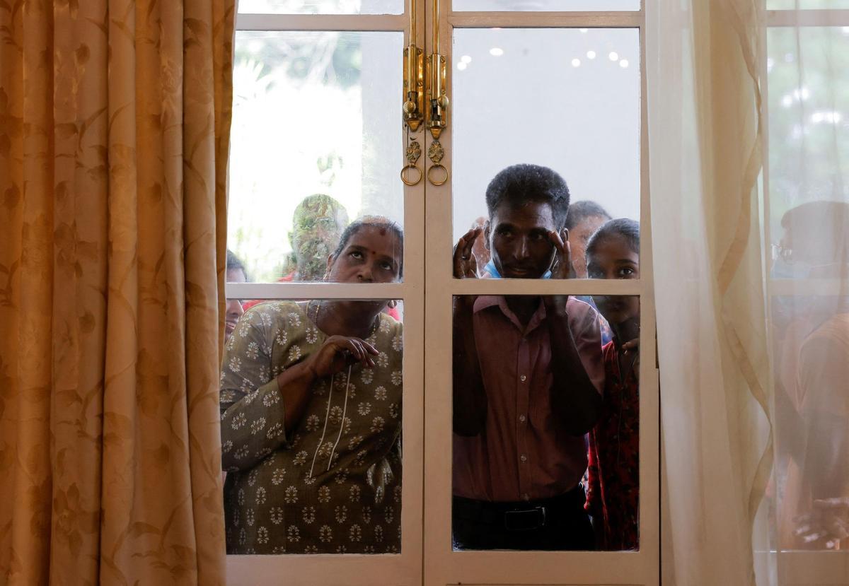 Un grupo de personas mira a través de una ventana durante una visita a la casa presidencial después de que los manifestantes entraran en el edificio.