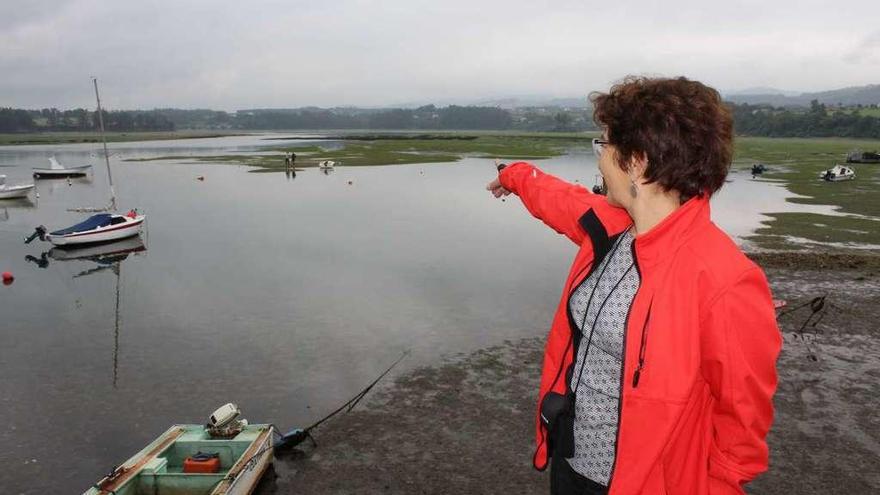 Carmen Rodríguez señala la zona donde se realizó la siembra, con dos técnicos trabajando al fondo.