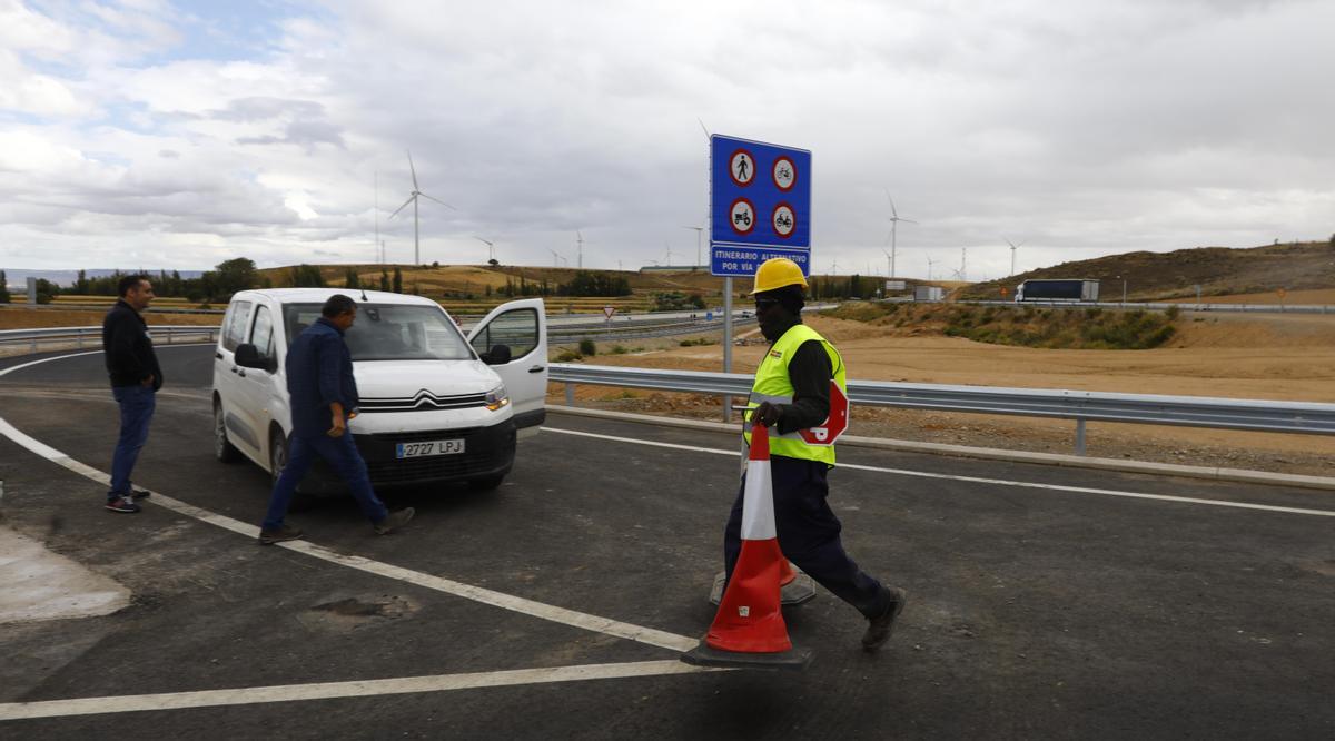 El trabajador Issa Kamara, de Mauritania, retira los pivotes que impedían el paso al nuevo tramo de autovía.