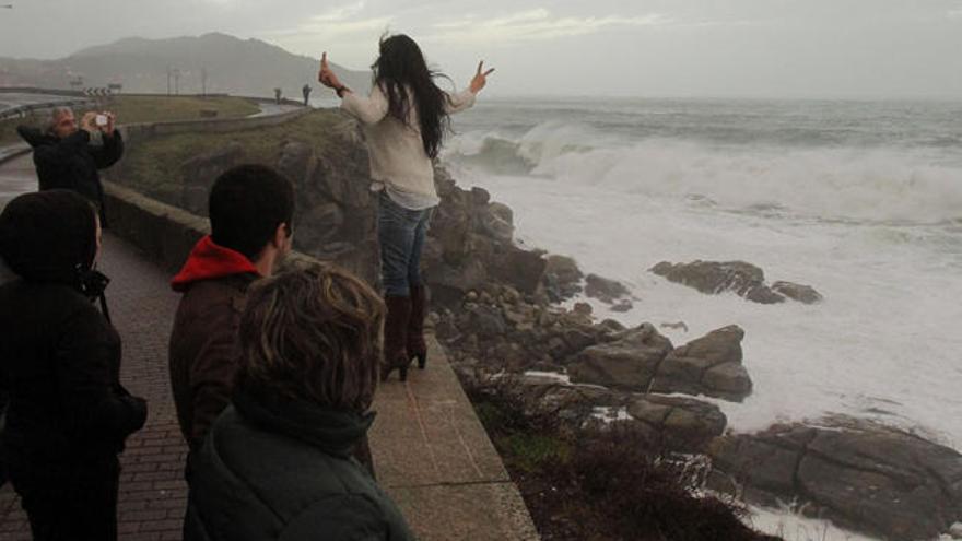 Un grupo de personas contempla las olas en el paseo marítimo en las afueras de Baiona. // R. Grobas