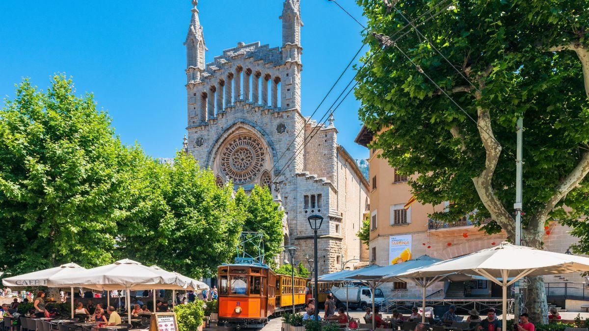 El famoso tranvía de madera por las calles de Sóller ante la iglesia de San Bartolomé.