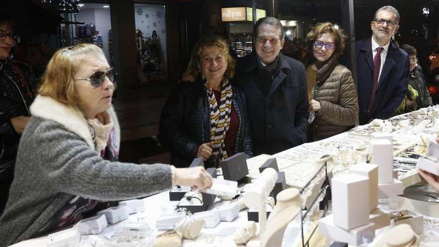 Arriba, Caballero en el mercado navideño de O Calvario. A la izquierda, Corina Porro y Roberto Giráldez, de la Asociación de Comerciantes de Teis. // R. Grobas