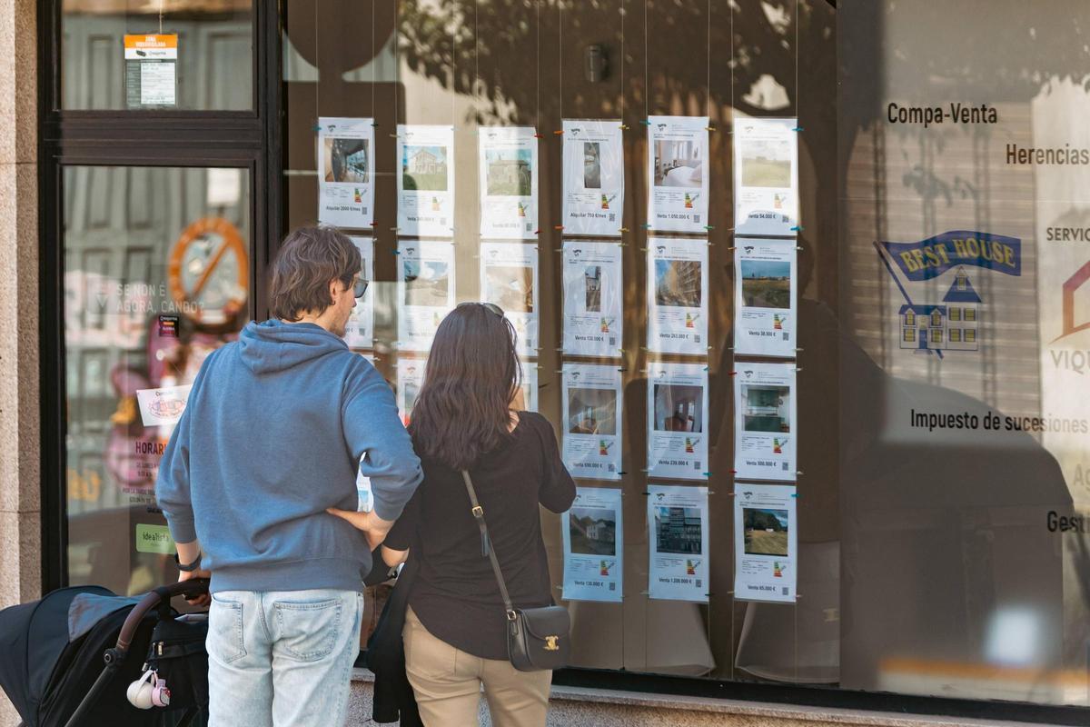 Una pareja ante el escaparate de una inmobiliaria de Santiago.