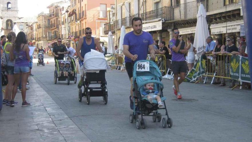 Padres empujan las sillas de paseo y los cochecitos de sus hijos durante la carrera.