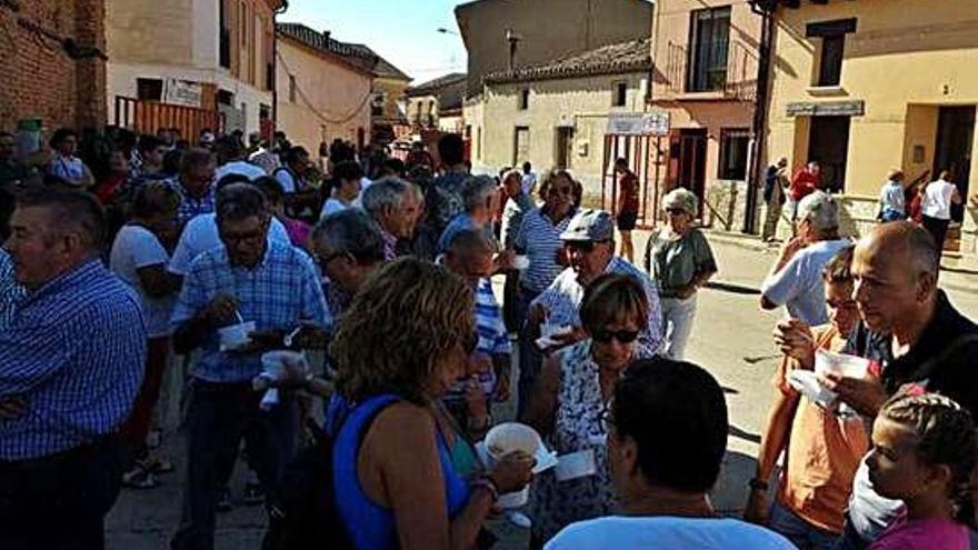 Vecinos de Morales degustan sopas de ajo en recipientes de plástico durante las fiestas del pasado año.