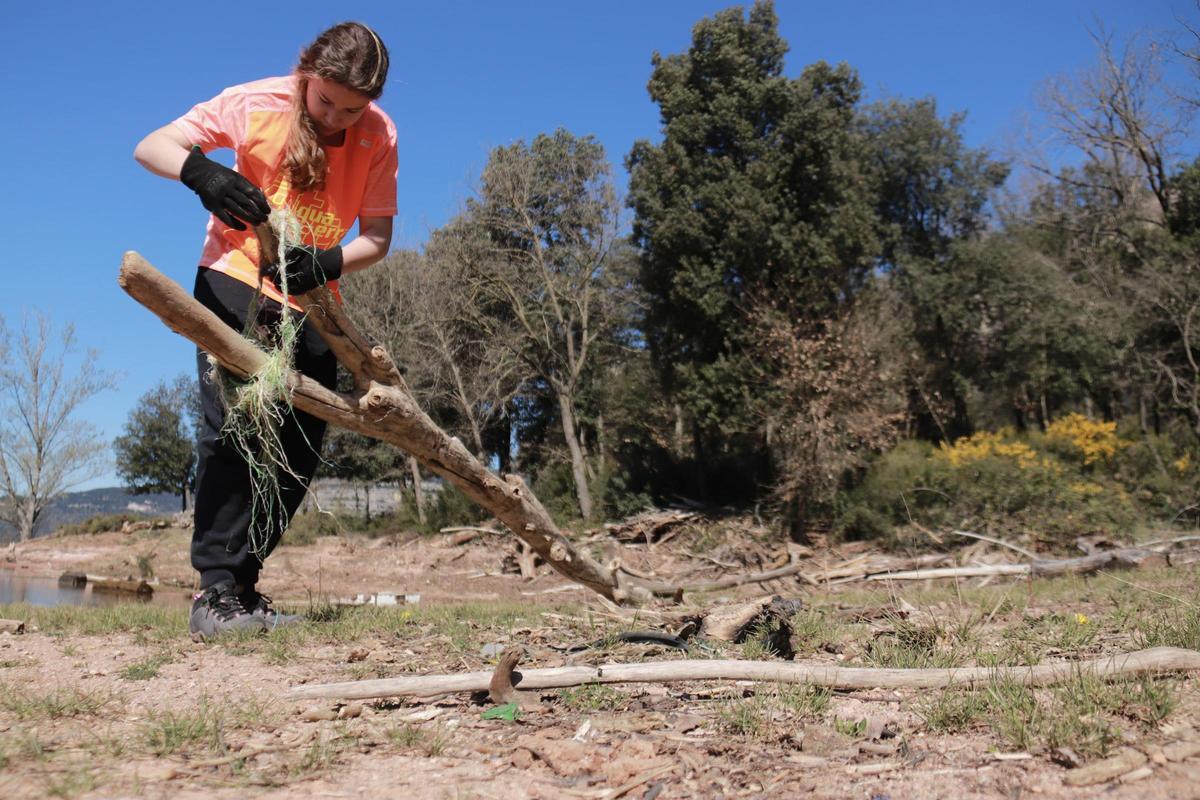 Una voluntaria retira una red de restos acumulados en el pantano de Sau.