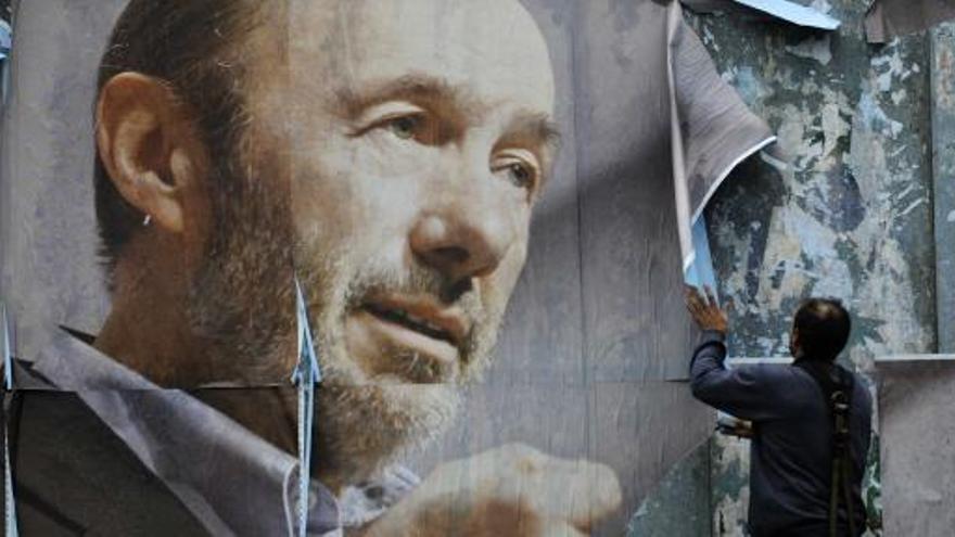 Un operario retira un cartel electoral de Rubalcaba en Oviedo.