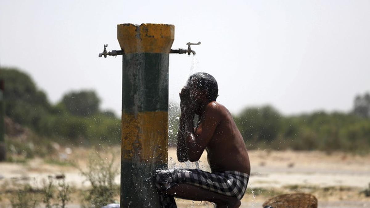 Un trabajador indio se refresca bajo un grifo una calurosa tarde en Amritsar (India).