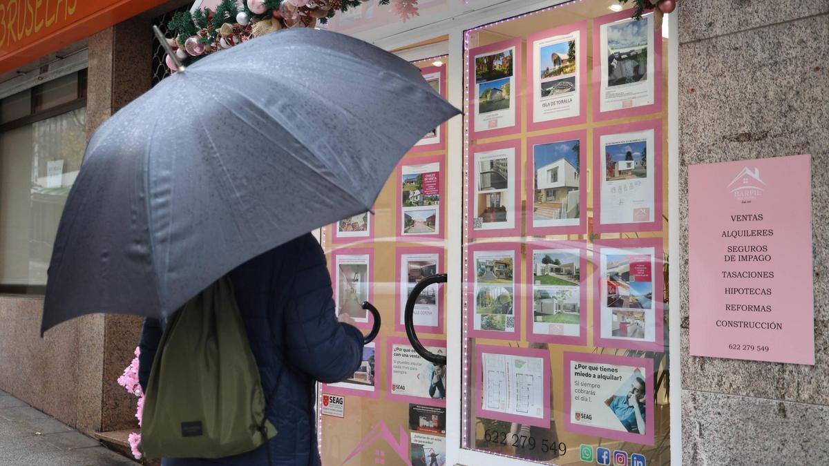 Una persona mirando el escaparate de una inmobiliaria.