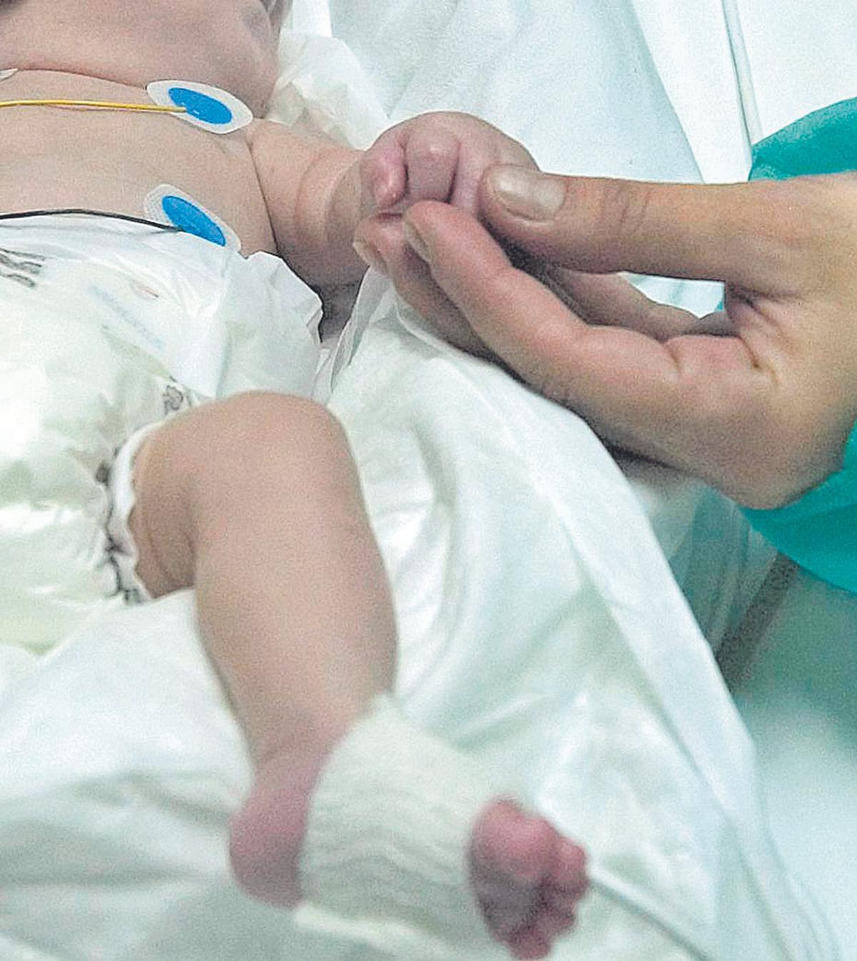 Una madre agarra la mano de su hijo recién nacido