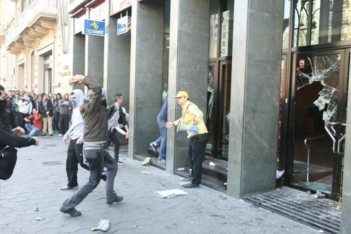 Un manifestant retreu la seva acció a un violent després de trencar vidres d’una sucursal bancària.