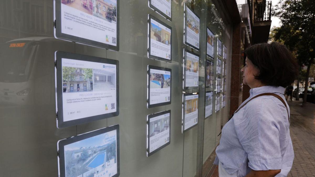 Una mujer mira anuncios de pisos en venta de una inmobiliaria en Barcelona.  | ELISENDA PONS
