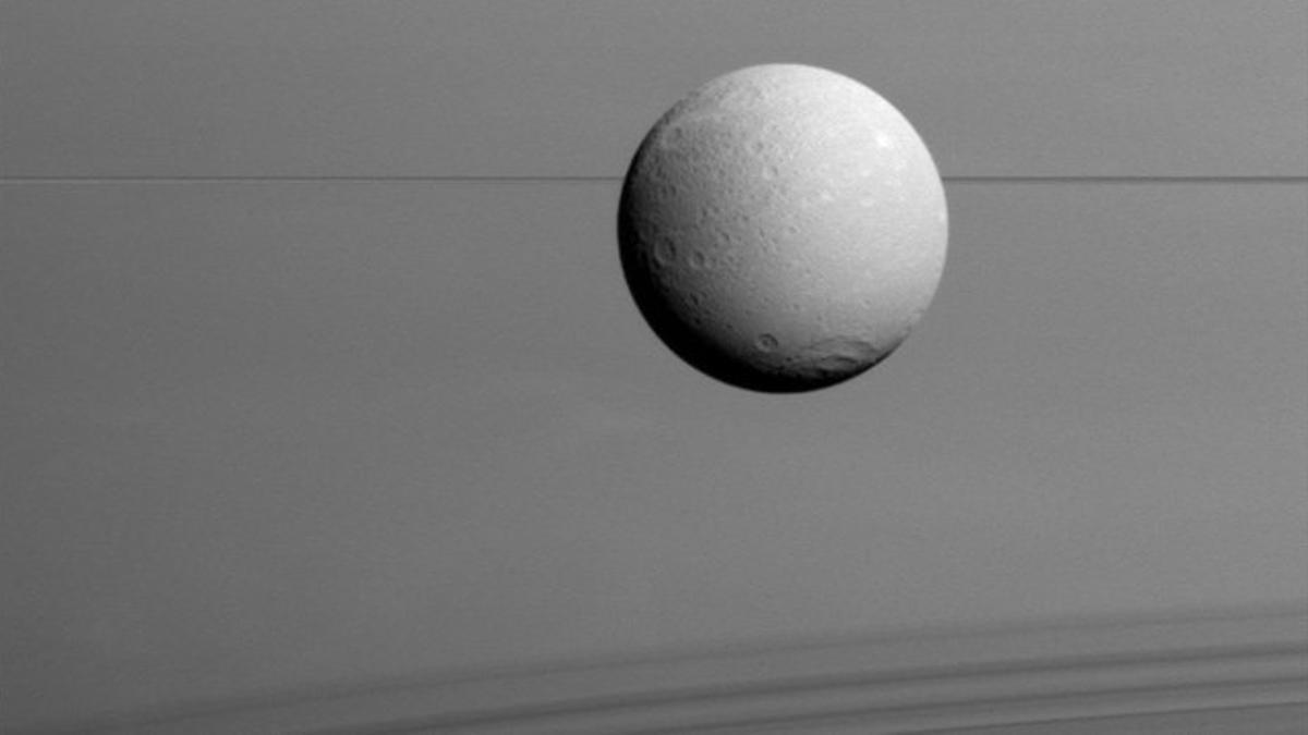 Panorámica de Dione con los anillos de Saturno al fondo