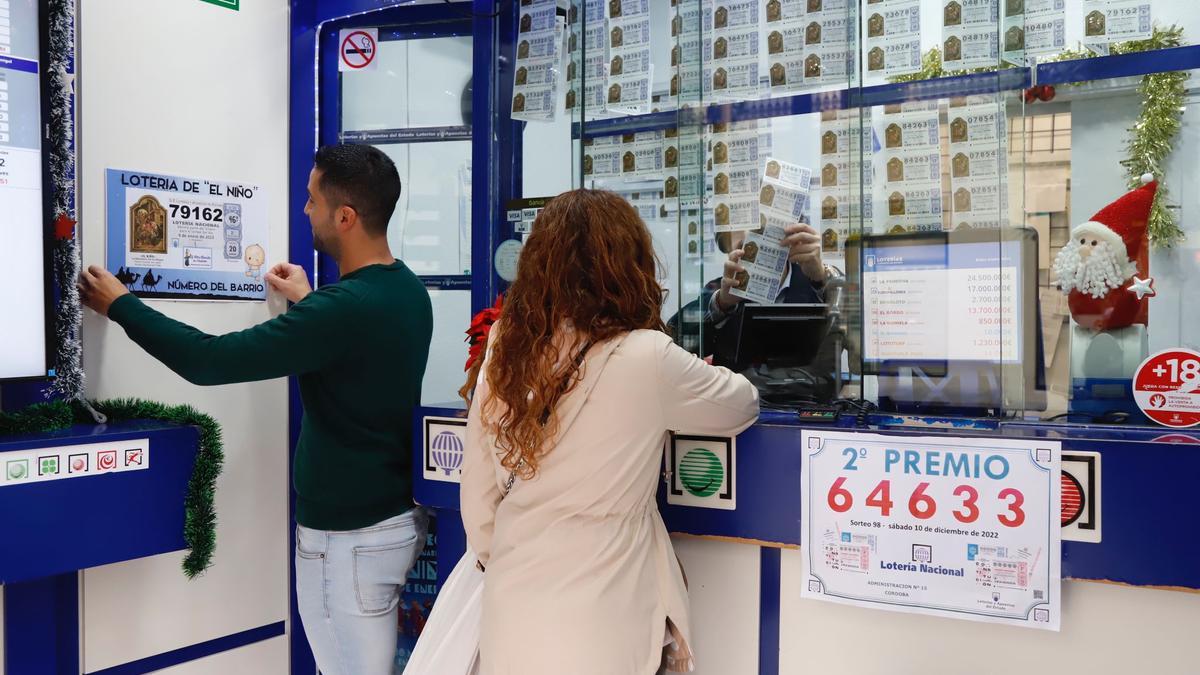 Un lotero cuelga el cartel de la Lotería de El Niño, tras la ausencia de premios de Navidad.