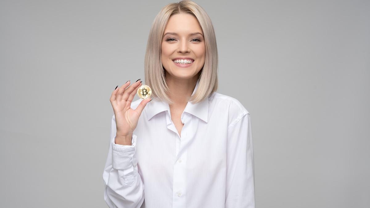 Una mujer posa con una moneda que representa un Bitcoin