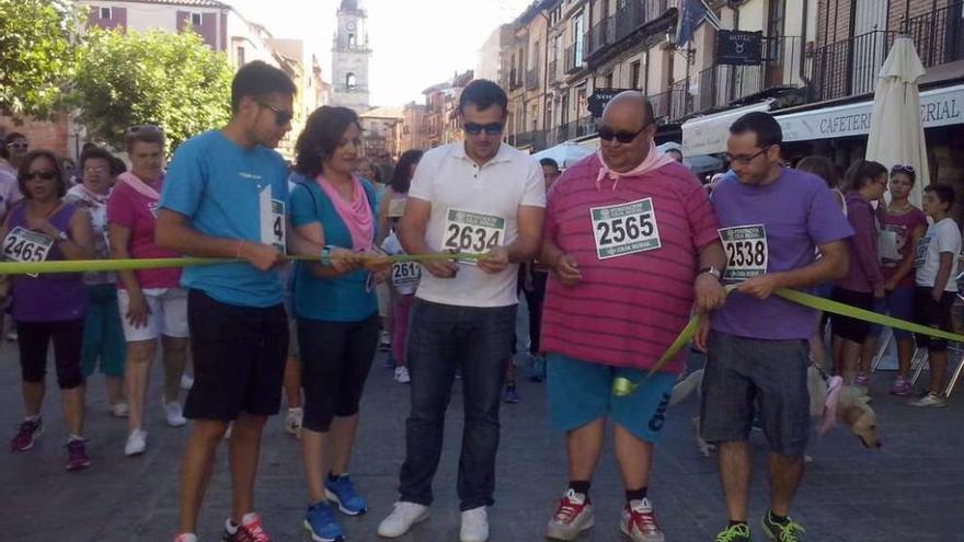 El alcalde, en el centro, corta la cinta para dar salida a la marcha.