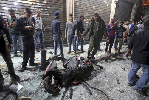 A motorcycle is seen amid residents inspecting a damaged area caused by two explosions in Beirut's southern suburbs, Lebanon