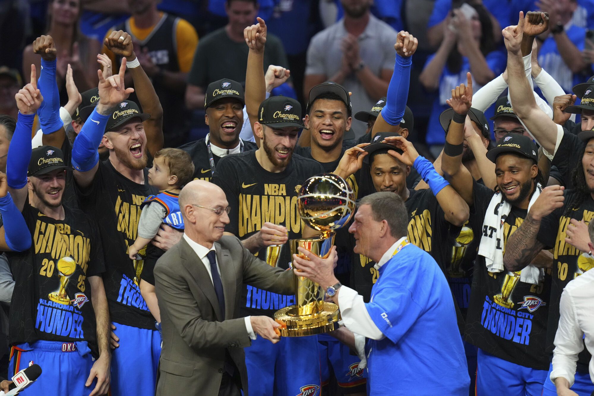 Clay Bennett, center right, chairman the ownership group of the Oklahoma City Thunder, receives the Larry O'Brien Championship Trophy from NBA Commissioner Adam Silver, center left, after winning the NBA basketball championship with a Game 7 victory against the Indiana Pacers Sunday, June 22, 2025, in Oklahoma City. (AP Photo/Nate Billings)
