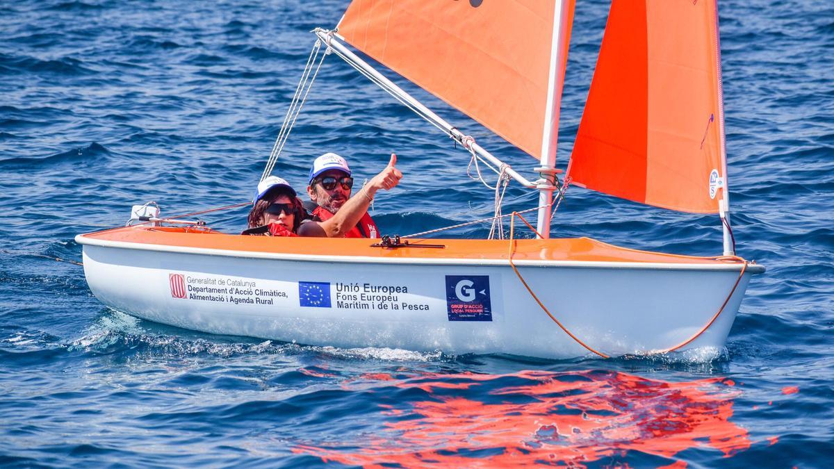 Dues persones naveguen en una emabarcació de vela adaptada per a persones amb discapacitat en el projecte Per un mar accessible