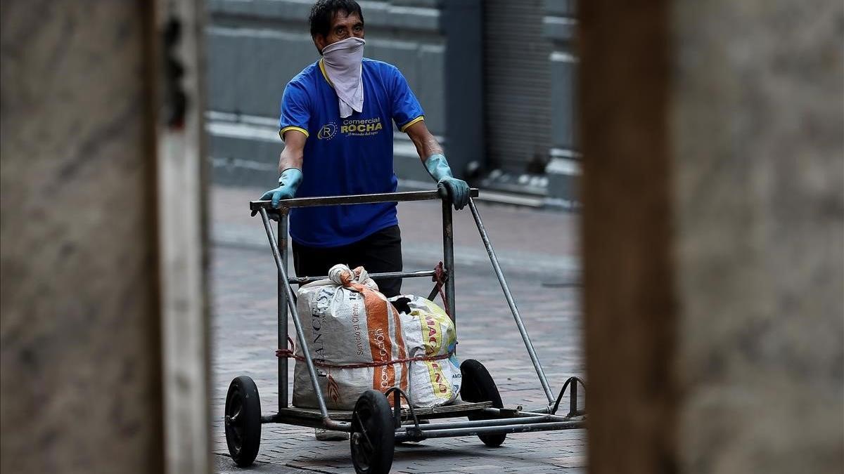 Un ciudadano de Quito trata de protegerse del contagio de coronavirus mientras traslada alimentos por el centro de la ciudad.