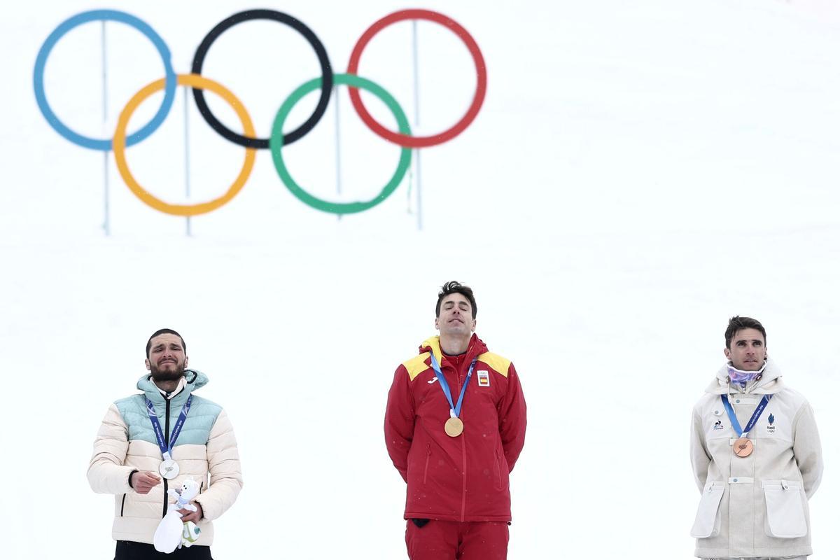 Spain's Oriol Cardona Coll, center, listens to the national anthem after winning the gold medal in a ski mountaineering men's sprint final, with silver medalist Individual Neutral Athlete Nikita Filippov, left, and bronze medalist France's Thibault Anselmet, at the 2026 Winter Olympics, in Bormio, Italy, Thursday, Feb. 19, 2026. (AP Photo/Gabriele Facciotti)