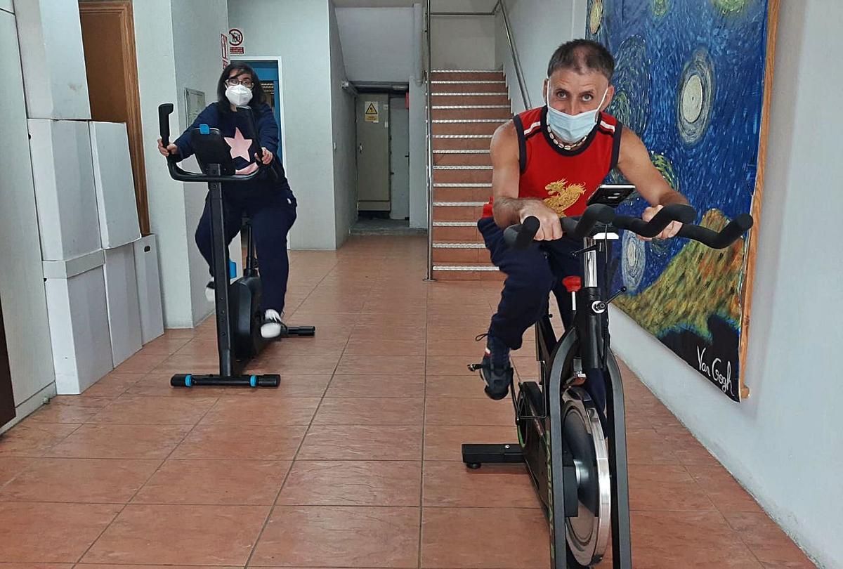 Dos usuarios del centro Juan María practican ejercicio en medio de un pasillo. |   // CENTRO JUAN MARÍA