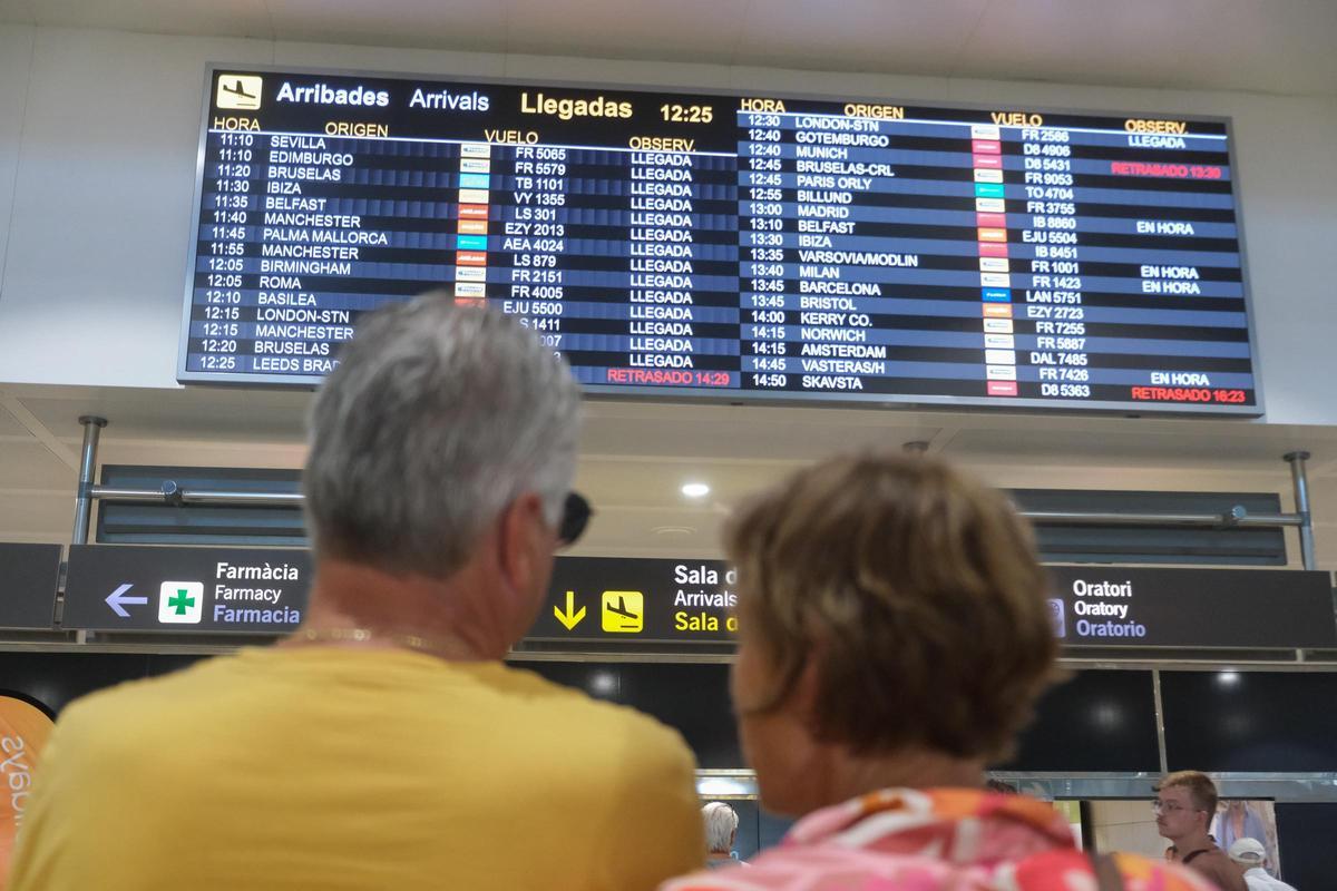 Dos pasajeros miran el panel informativo.