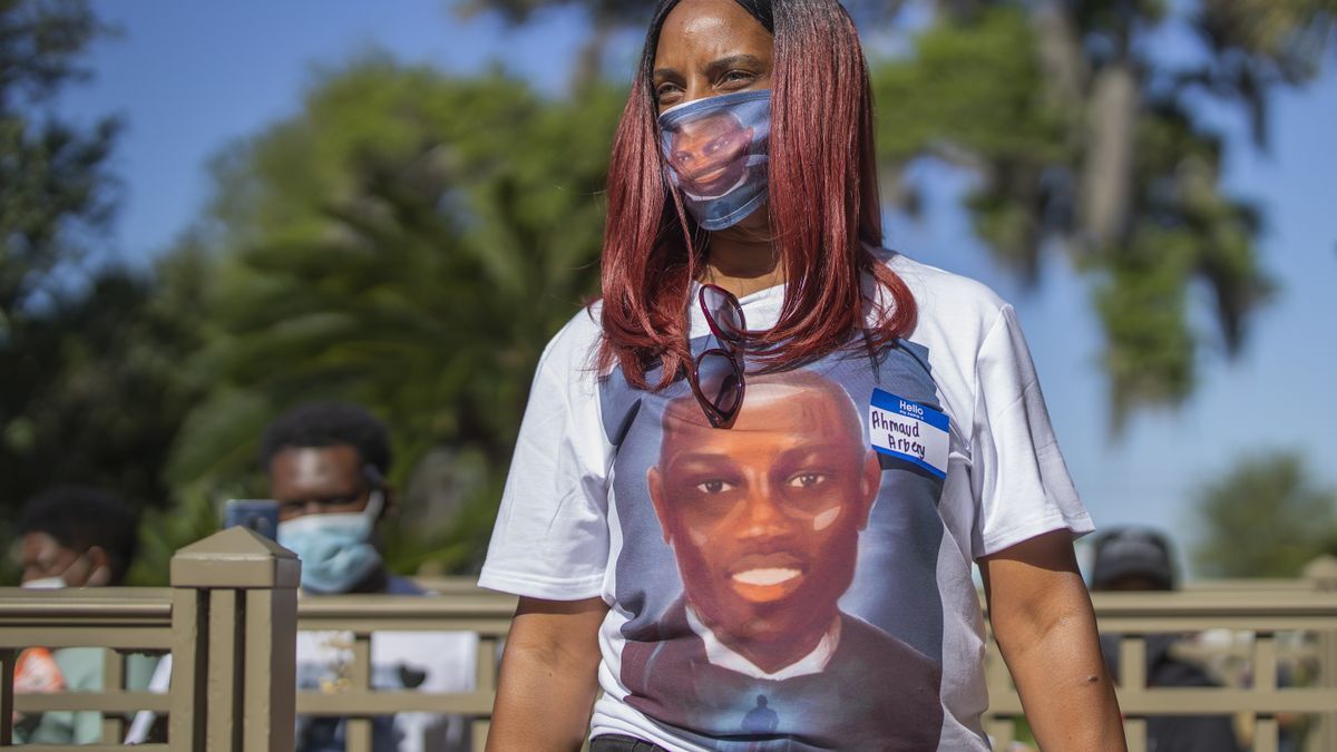 Una mujer utiliza una mascarilla y una camiseta con el rostro de Ahmaud Arbery.