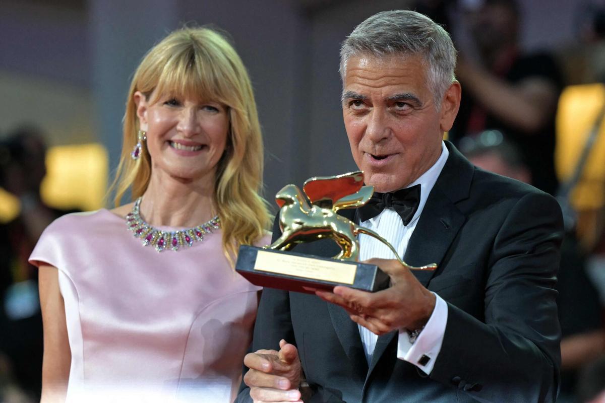 El actor y cineasta estadounidense George Clooney posa junto a la actriz estadounidense Laura Dern tras recibir el León de Oro a toda una carrera