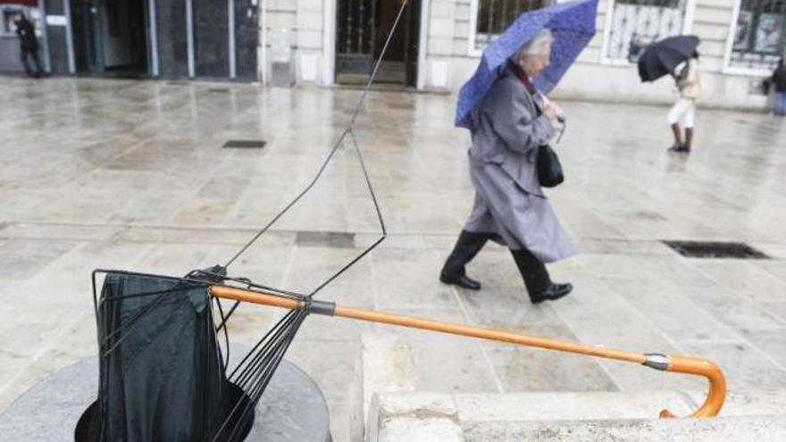 Varias personas se protegen del viento y de la lluvia, ayer, en A Coruña. / fran martínez