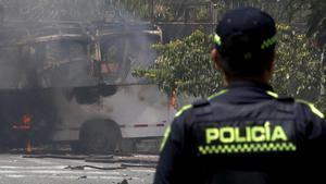 Un policía colombiano observa un vehículo afectado por una explosión este viernes en Cali.