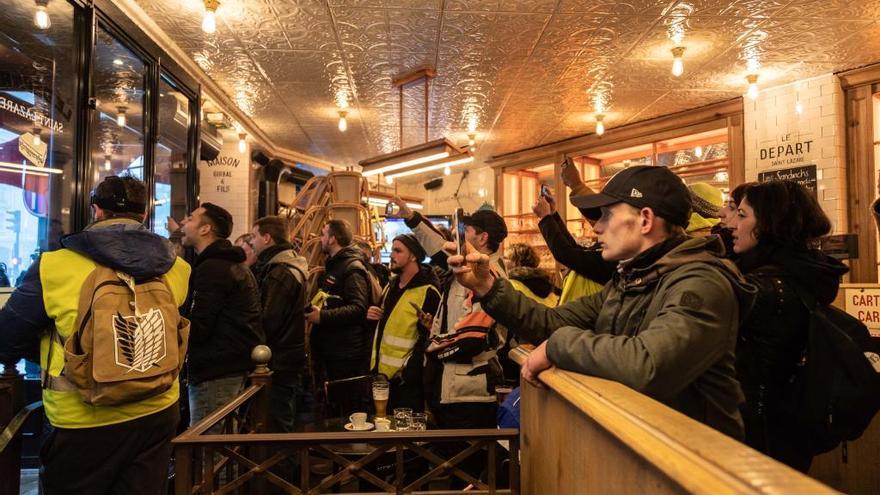 Manifestantes observan los disturbios desde de un café.