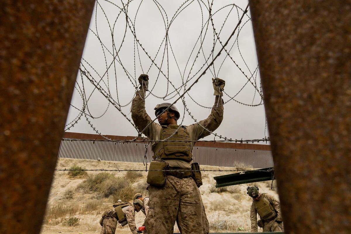 Un integrante del ejercito de Estados Unidos refuerza un muro con alambre de púas este jueves, en la frontera con la ciudad de Tijuana
