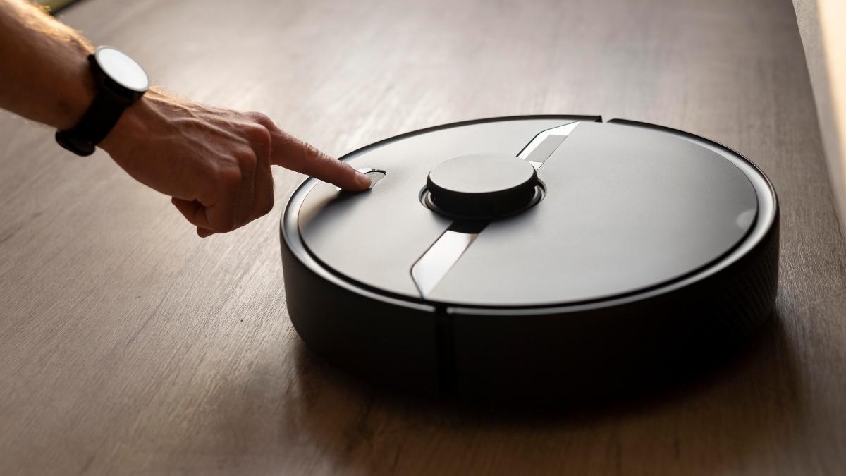 Una persona activa el robot inteligente para limpiar el suelo de su casa