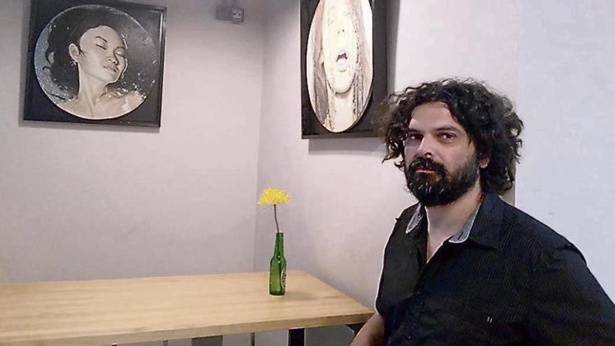 Carlos Adeva posa junto a dos de las pinturas que expone en un bar de la ciudad.
