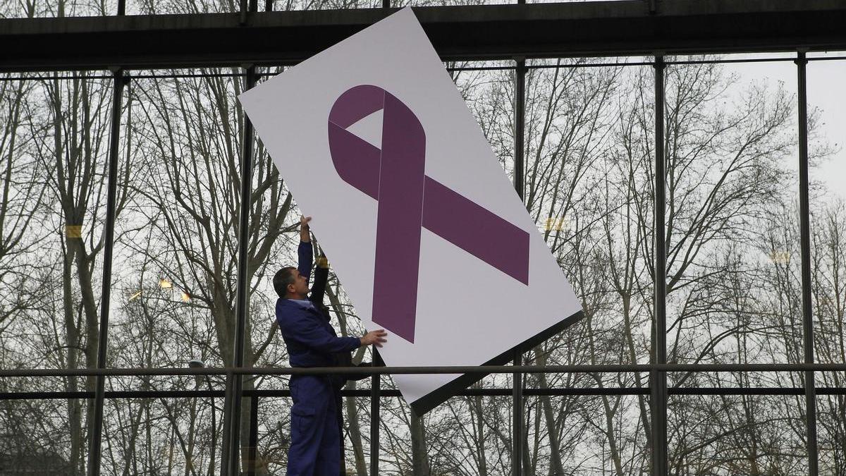 Un hombre sujeta un lazo morado, símbolo de la lucha contra la violencia machista.