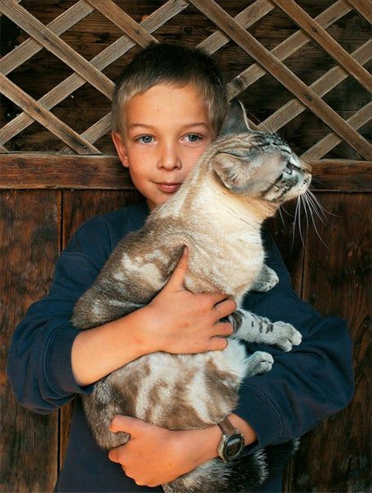 Un  niño posa con su gato  en su casa de la aldea  de Le Mont.