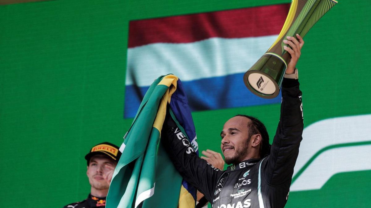 Hamilton celebra la victòria en el podi del circuit d’Interlagos sota la mirada de Verstappen. | EFE/ANTONIO LACERDA