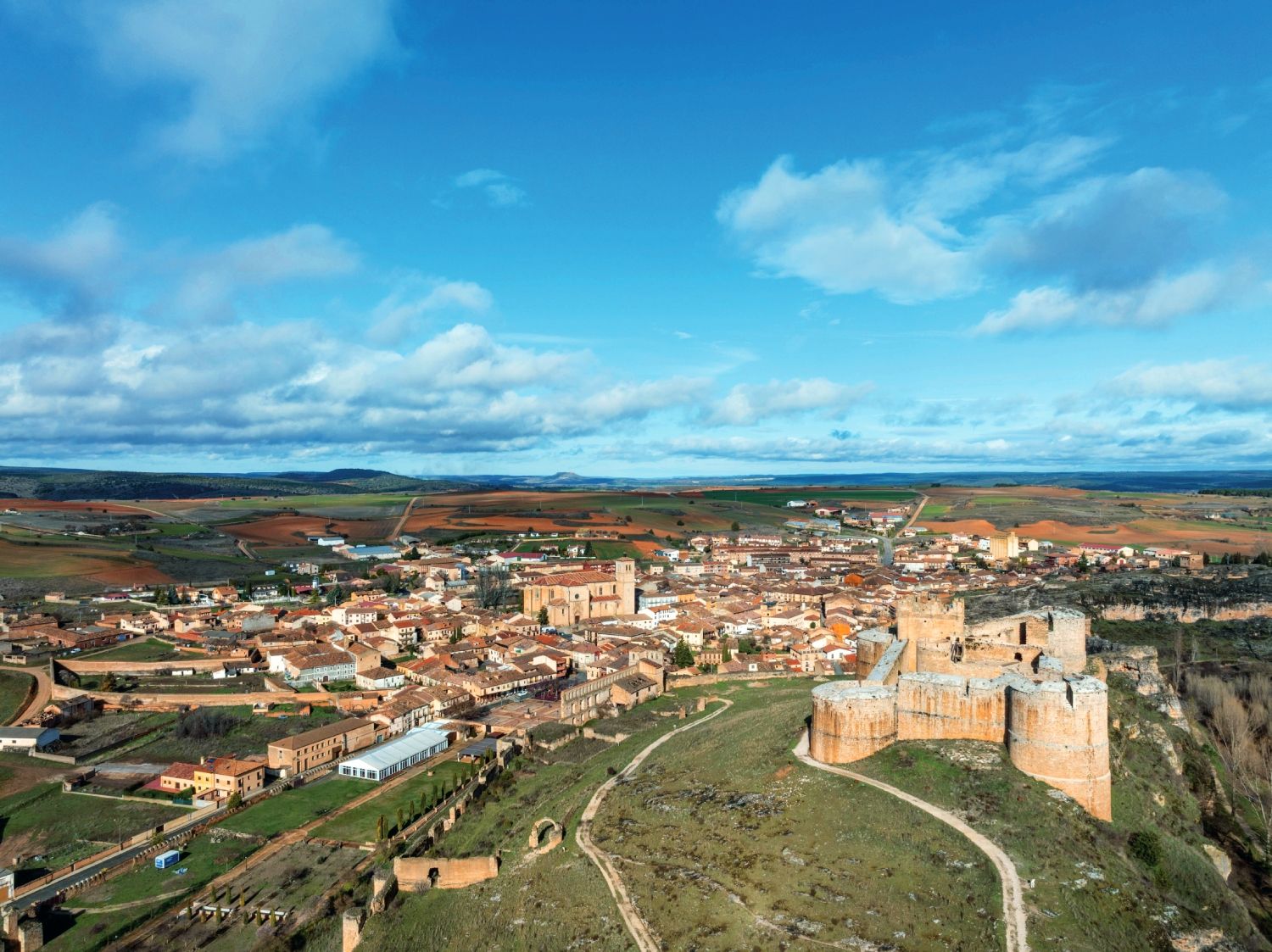 Vista del castillo de Berlanga de Duero con el casco histórico del pueblo al fondo. Esta imponente fortaleza renacentista, construida sobre una anterior estructura medieval, formaba parte del sistema defensivo del Duero en tiempos del Cid. Hoy domina el paisaje soriano como símbolo del poder señorial y la historia fronteriza de la región.