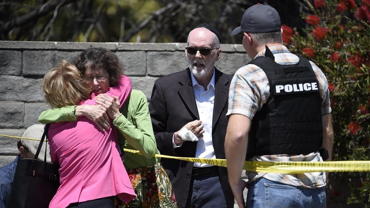 Dos personas se abrazan en la zona acordonada de la sinagoga de Poway, donde ha habido un tiroteo el 27 de abril del 2019