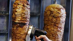 Un hombre corta carne de kebab. 