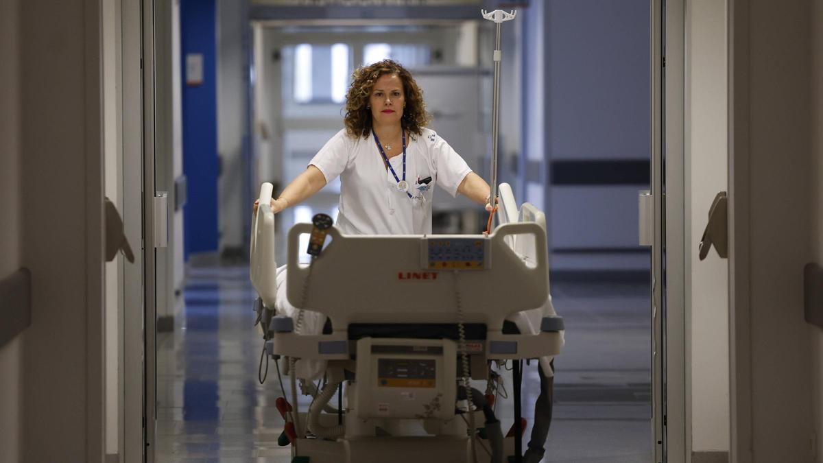 Una celadora durante el traslado de un paciente en un hospital.