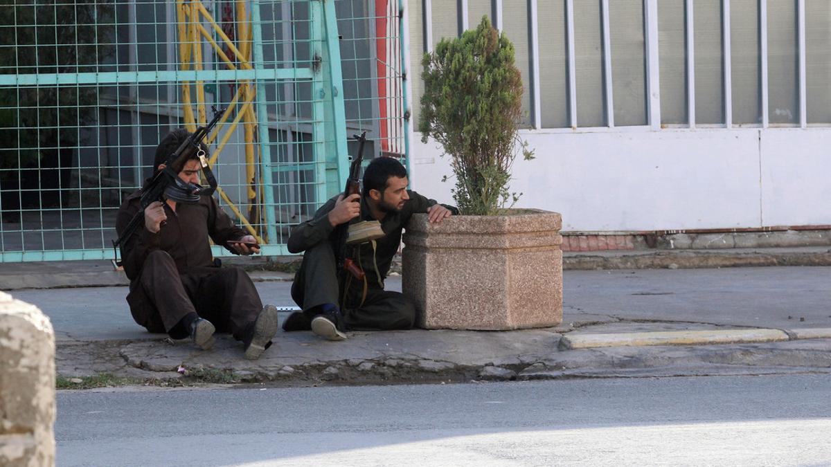 Kurdish security personnel take cover at a site of an attack by Islamic State militants in Kirkuk