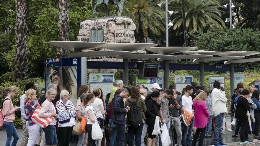 Un gran grupo de turistas espera el autobús en Plaza España de Palma.