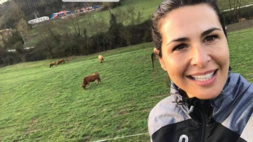 Nuria Roca posando con unas vacas de fondo mientras hacía la ruta entre Las Caldas y Oviedo en bicicleta.