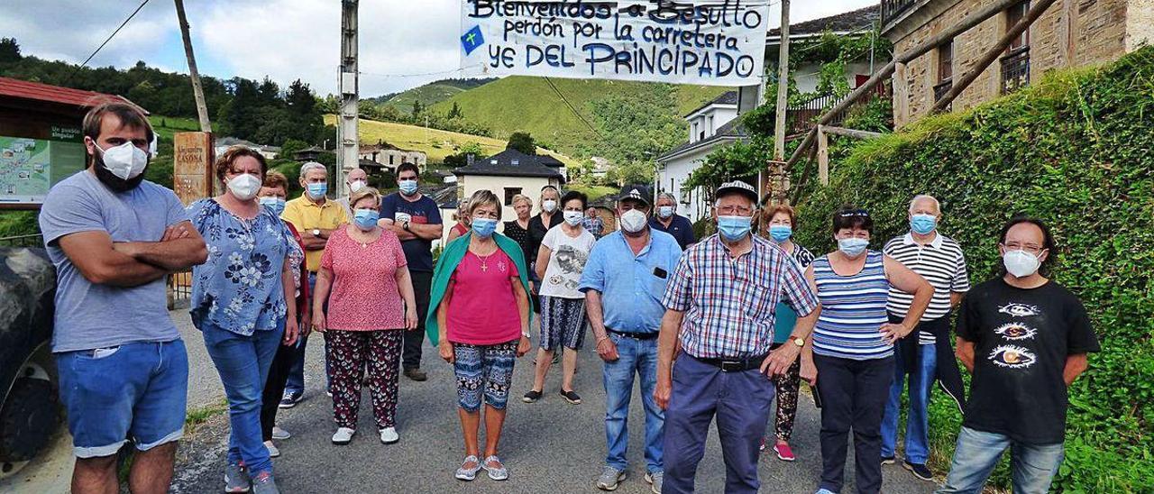 Vecinos de Besullo, ayer, a la entrada del pueblo, bajo su cartel de bienvenida.